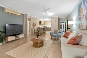 a living room with a couch and a tv at Azure at The Edge, Steps to the Esplanade in Cairns North