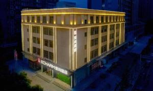a large white building with lights on it at night at Echarm Hotel Wuhan High-speed Rail Peace Park Metro Station in Wuhan