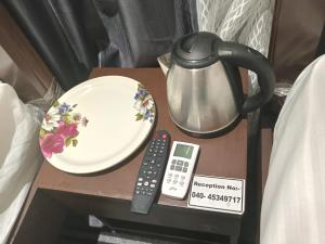 a table with a tea pot and a plate and a remote control at Silk White in Hyderabad +10 photos