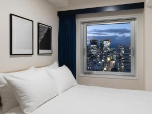 a bedroom with a white bed and a window at Brackets Hotel Osaka Hommachi in Osaka