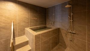 a bathroom with a shower with brown tiles at Ponshu Hotel Suimu in Tokamachi +42 photos