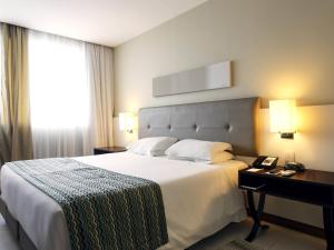 a hotel room with a large bed and a window at Mercure Salvador Pituba in Salvador