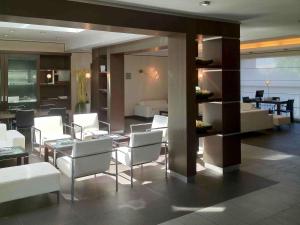 a living room with white chairs and a dining room at Mercure Bergamo Aeroporto in Stezzano
