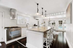 a white kitchen with a large island with a stove at Casa Di Angelina By Coast Hosting in Blackwall