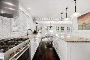 a kitchen with white cabinets and a stove top oven at Casa Di Angelina By Coast Hosting in Blackwall