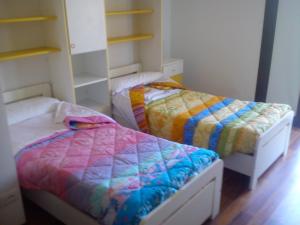 2 camas individuales en una habitación con estanterías en Casa Vacanza Holiday en Pieris