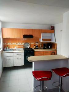 a kitchen with a counter and two red bar stools at Bonita casa amueblada Cuautitlán in Cuautitlán