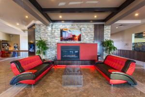 a lobby with two red leather couches and a fireplace at Ramada by Wyndham Edmonton Yellowhead NW in Edmonton