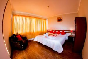 una camera da letto con un grande letto bianco e una sedia di Cusco House a Cuzco