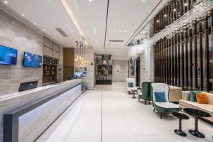 a lobby with a bar with green chairs at City Comfort Inn Suzhou Wujiang Development Zone Yundong in Suzhou