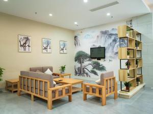 a living room with two chairs and a tv on a wall at GreenTree Inn Express Suzhou Luzhi Ancient Town Scenic Area Xiaoshi Road in Suzhou