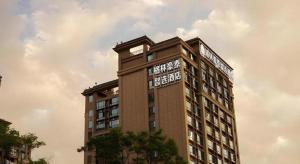 a tall building with a clock on the top of it at GreenTree Inn Express Kunming East Passenger Station Huazhicheng in Kunming