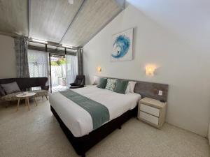 a bedroom with a bed and a chair and a window at Nautilus Beach Resort by Charlesworth in Coffs Harbour