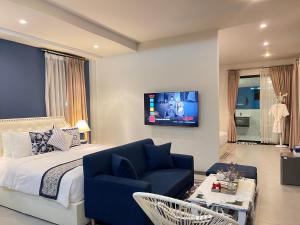 a bedroom with a bed and a couch and a tv at Romlaphass Boutique Villa in Kalasin