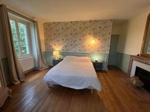 Un dormitorio con una cama blanca y una chimenea en Grande maison Albuconis,  8 fotos más