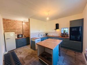 a kitchen with blue cabinets and a white refrigerator at Grande maison Albuconis in Saint-Oradoux-près-Crocq