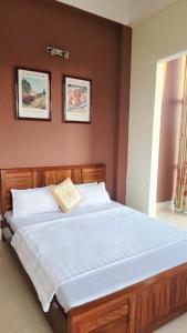 a large bed in a bedroom with two pictures on the wall at Roxbury house in Bản Múa