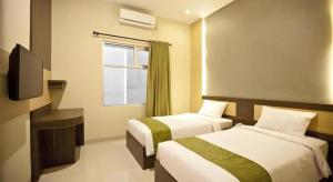 a hotel room with two beds and a television at dPalma Hotel in Bandung +144 photos
