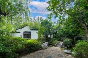 un jardin avec une maison blanche et des arbres dans l'établissement DoubleTree By Hilton Wuxi, à Wuxi