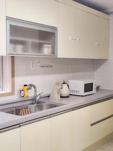 a kitchen with a sink and a microwave at 더휴 광안 in Kwangan-dong
