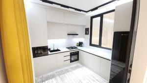 サマルカンドにあるSamarkand Apartmentsの白いキャビネットと窓のあるキッチン