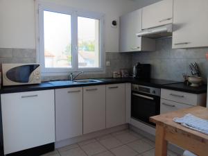 a kitchen with white cabinets and a sink and a microwave at Maison paisible pour 5 pers. avec vue sur le Lay - FR-1-476-249 in LʼAiguillon-sur-Mer +11 photos