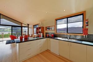 a large kitchen with two windows and a counter top at Moon River in Gardners Bay