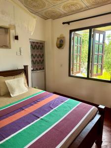 a bedroom with a colorful bed with a window at Stay Happy at Chathurni Villa, Ahangama in Ahangama