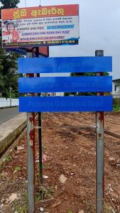 a blue sign sitting on the side of a road at Pirivena Garden Resort - AC Units, Kitchen, Attached Bath Room, & WiFi in Boralesgamuwa +2 photos