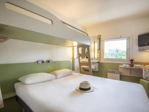 a bedroom with a bed with a hat on it at IBIS Budget Aix en Provence Est Le Canet in Meyreuil +61 photos