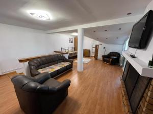 sala de estar con muebles de cuero y TV de pantalla plana en Casa Raicu, en Ploieşti