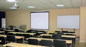 an empty classroom with tables and chairs and a white screen at Jinjiang Inn JiNan Daminghu New Scenic Area Lishan Road in Jinan