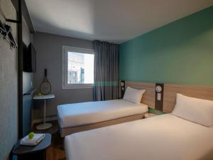 Una pequeña habitación con dos camas y una ventana. en ibis budget Nice Aeroport, en Niza