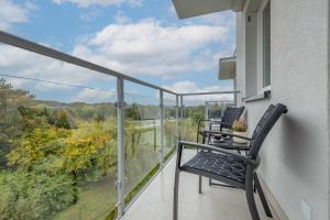 einen Balkon mit 2 Stühlen und Waldblick in der Unterkunft Stylish Apartment in Kołobrzeg with Air Conditioning and Parking by Noclegi Renters in Luboszyce