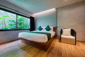 ein Schlafzimmer mit einem Bett, einem Fenster und einem Stuhl in der Unterkunft Z Garden Hotel Managed by H Hospitality in El Nido