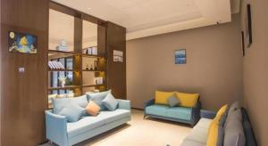 a living room with two blue couches and yellow pillows at Borrman Hotel Nanning Railway Station in Nanning