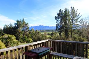 una panchina su una terrazza di legno con montagne sullo sfondo di Freestone House a Manapouri