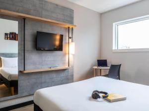 a hotel room with a bed and a tv on a wall at ibis budget Paris Porte de Montreuil in Montreuil