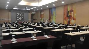 a room full of tables and chairs with cups on them at Zoom Dharmahusada Hotel in Surabaya