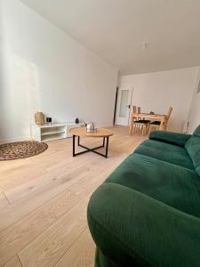 a living room with a green couch and a table at Charmant appartement tout confort in Châteaubriant