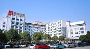 a parking lot with cars parked in front of a large building at Echarm Hotel Nanning Nationalities Square Metro Station in Nanning