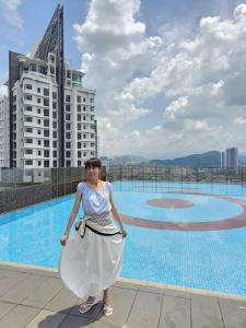a woman standing in front of a swimming pool at 3 Tower Ampang Suite in Kuala Lumpur