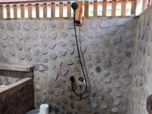 een douche in een badkamer met een stenen muur bij Pantai Naama Bungalow 