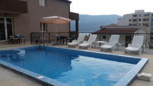 a swimming pool with chairs and a table and an umbrella at Apartments Lav Costas in Herceg-Novi