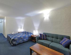 a living room with a couch and a bed at Alexandra Park Motor Inn in Bundaberg