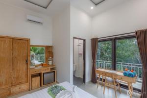 a bedroom with a bed and a desk and a window at Hanaka Riverside Ubud in Ubud
