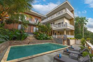 eine Außenansicht eines Hauses mit Swimmingpool in der Unterkunft Hanaka Riverside Ubud in Ubud
