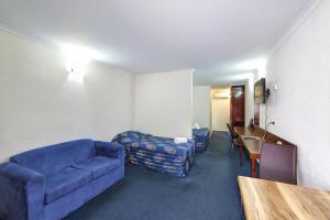 Alexandra Park Motor Inn في بوندابرج: غرفة معيشة مع أريكة زرقاء وطاولة