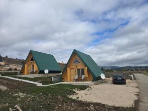 a house with a green roof on the side of a road at Summit chalets TL in Žabljak