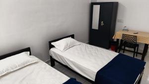 a bedroom with two beds and a table and a table and chair at Pynadath Square in Adūr